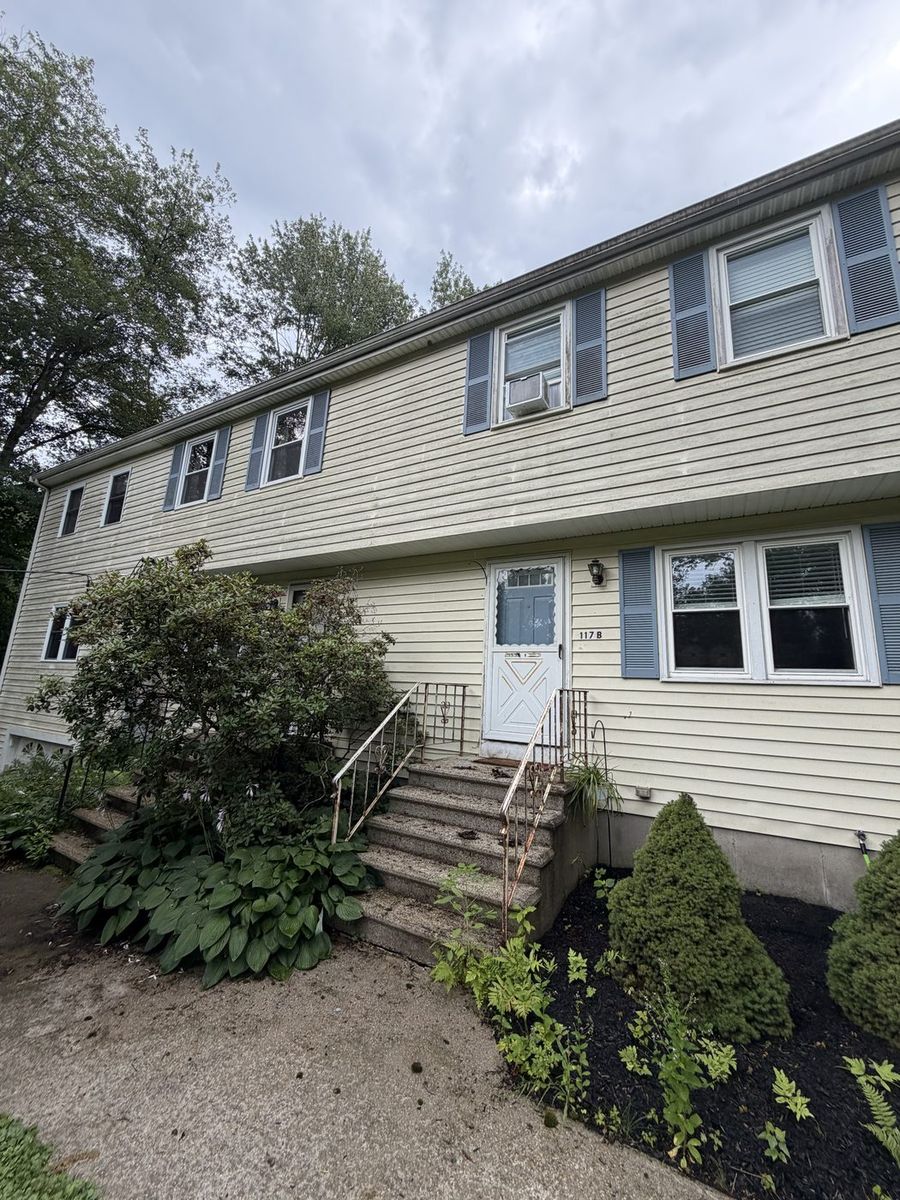 House siding with dirt and green algae streaking before power washing